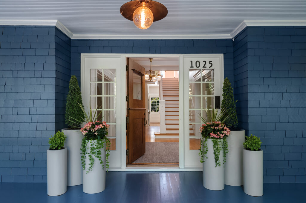 The front porch of a home for sale with new paint and potted flowers