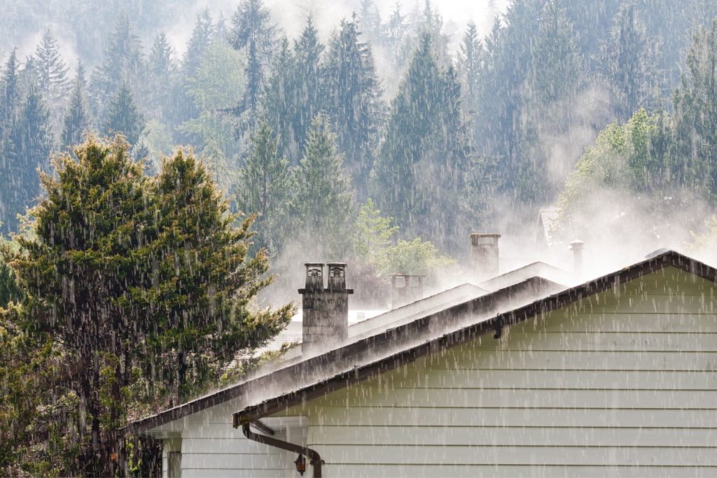 rain pouring on the roof of a home that can cause water damage
