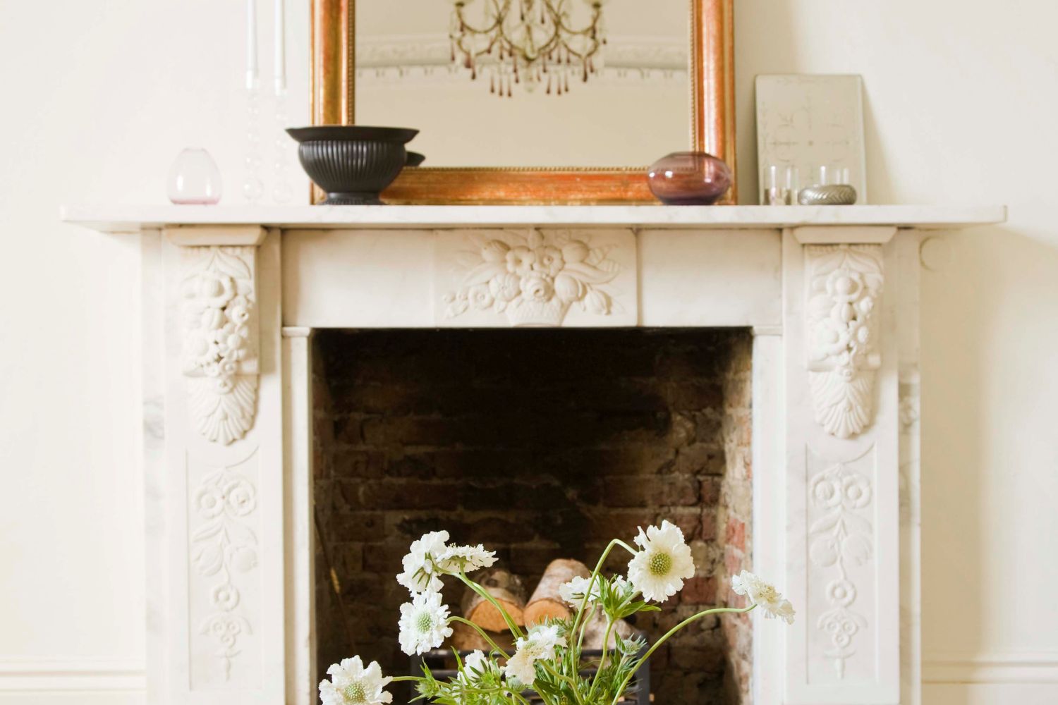 A cream vintage fireplace with a bouquet of flowers in front of it